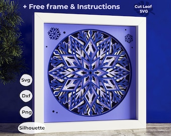 Könnte beinhalten: Ein mehrschichtiges Papierkunstwerk mit einem Schneeflocken-Design in Blau- und Weißtönen, das in einem weißen Rahmen eingefasst ist. Das Kunstwerk enthält den Text "+ Free frame & Instructions" und Dateityp-Optionen: SVG, DXF, PNG und Silhouette.