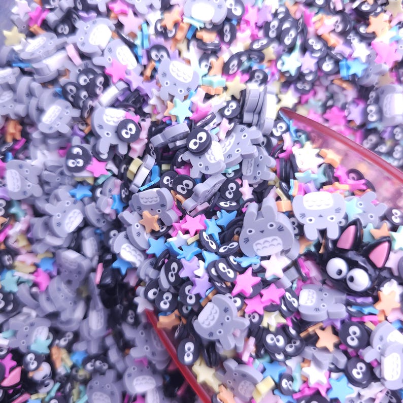Puede incluir: Primer plano de una variedad de amuletos de resina de colores, incluyendo estrellas y personajes de dibujos animados. Los amuletos son de varios colores, incluyendo rosa, azul, amarillo y verde.