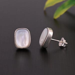 May include: A pair of silver earrings with white mother of pearl rectangular stones.