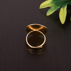 Pode incluir: Um anel ajust&aacute;vel de ouro com uma parte superior redonda e plana. O anel &eacute; feito de metal e tem um acabamento liso.