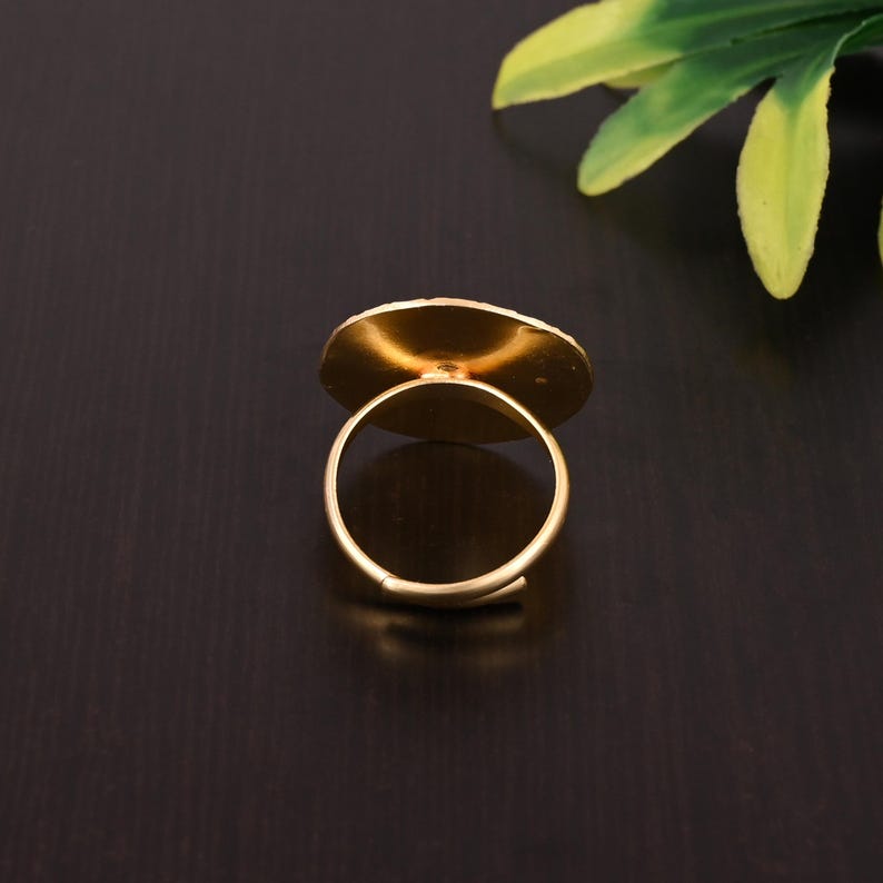 Pode incluir: Um anel ajust&aacute;vel de ouro com uma parte superior redonda e plana. O anel &eacute; feito de metal e tem um acabamento liso.