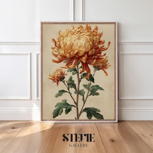 Könnte beinhalten: Ein rechteckiger Wandkunstdruck mit einer großen, detaillierten Illustration einer gold-orangen Chrysantheme mit grünen Blättern und Stielen auf cremefarbenem Hintergrund, eingefasst von einem dünnen, dekorativen braunen Rahmen.