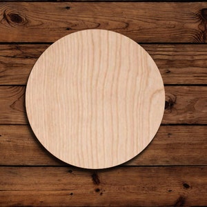 May include: A round, unfinished wood circle, with a light brown color and a wood grain pattern. The circle is on a dark brown wood background.