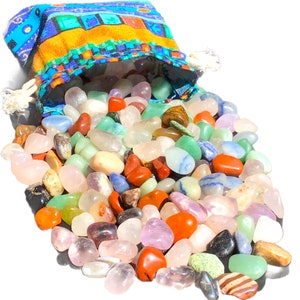 Könnte beinhalten: Ein Stoffbeutel mit Kordelzug, verziert mit blauen, gelben und orangen Mustern, verstreut eine Sammlung polierter Edelsteine. Die Edelsteine sind in verschiedenen Farben erhältlich, darunter Rot, Orange, Grün, Blau, Lila und Transparent.