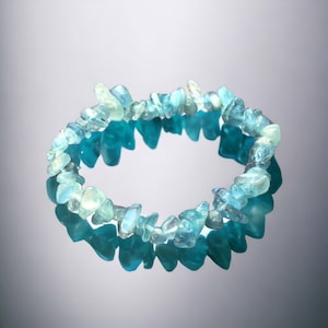 Könnte beinhalten: Ein hellblaues Armband aus Aquamarin-Chips. Das Armband besteht aus kleinen, unregelmäßig geformten Aquamarin-Chips, die auf einer durchsichtigen Gummikordel aufgefädelt sind.