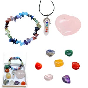 Könnte beinhalten: Ein Set aus sieben Chakra-Steinen, darunter ein rosafarbener herzförmiger Rosenquarz, ein blauer Lapislazuli, ein grüner Aventurin, ein gelber Citrin, ein roter Karneol, ein violetter Amethyst und ein klarer Quarzkristall. Das Set enthält außerdem ein Regenbogen-Chakra-Armband und eine Regenbogen-Chakra-Halskette.