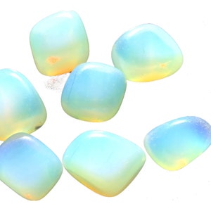 Peut inclure: Sept pierres d'opale lisses, polies et irisées dans différentes nuances de bleu et de blanc. Les pierres sont roulées et ont une forme naturelle et organique.