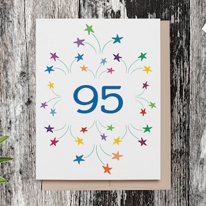 May include: A white card with a blue number "95" surrounded by a circle of colorful stars and green lines, resembling fireworks.