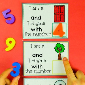 May include: A set of rhyming number cards for kids. Each card features a picture and a sentence that says "I am a ____ and I rhyme with the number ____". The cards are designed to help children learn about rhyming words and numbers.