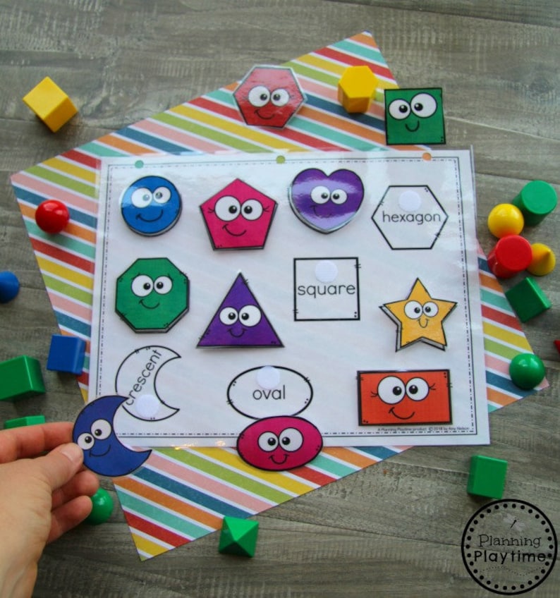 May include: A colorful set of felt shapes with happy faces, including a crescent, oval, hexagon, square, star, heart, and more. The shapes are arranged on a white sheet with the names of the shapes written below them.