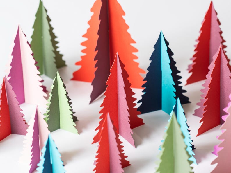K&ouml;nnte beinhalten: Eine Sammlung farbenfroher Weihnachtsb&auml;ume aus Papier in verschiedenen Rot-, Rosa-, Gr&uuml;n- und Blaut&ouml;nen. Die B&auml;ume sind in einer Gruppe angeordnet, wobei ihre gezackten Kanten eine festliche Darstellung bilden. Die B&auml;ume sind ein dekorativer Artikel.