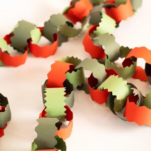 Puede incluir: Una guirnalda de cadena de papel en tonos naranja, verde y gris. Los eslabones est&aacute;n cortados con un borde decorativo, creando una decoraci&oacute;n festiva y colorida. Ideal para fiestas o decoraci&oacute;n de temporada.