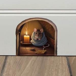 Puede incluir: Una pegatina de pared 3D de un ratón asomándose por un agujero en la pared. El ratón es marrón y gris y lleva una manta azul. El ratón está sentado en una habitación pequeña con una vela encendida y un suelo de madera.