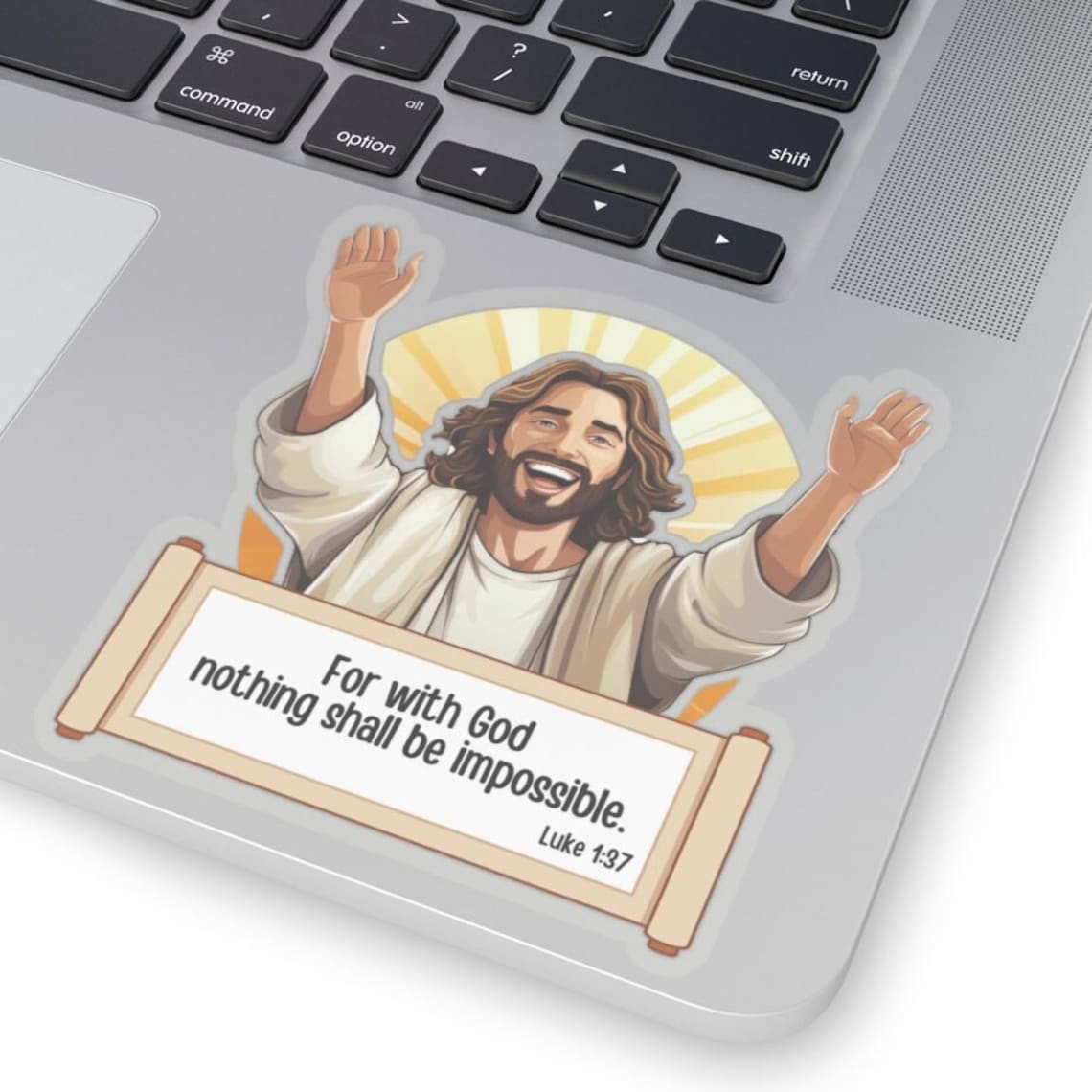 May include: A sticker featuring a joyful, cartoon-style depiction of Jesus Christ with arms raised.  The illustration is set against a radiant, sunburst background. Below the image, a parchment-like scroll displays the text: 'For with God nothing shall be impossible.'  Luke 1:37 is inscribed at the bottom of the scroll. The sticker is shown adhered to a silver laptop.