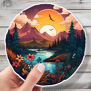 May include: A colorful illustration of a mountain landscape with a lake in the foreground. The sky is a vibrant orange and yellow with a few clouds. There are trees and flowers in the foreground and mountains in the background.