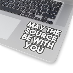 May include: A laptop computer with a sticker that says "May the source be with you" in a white font on a gray background.