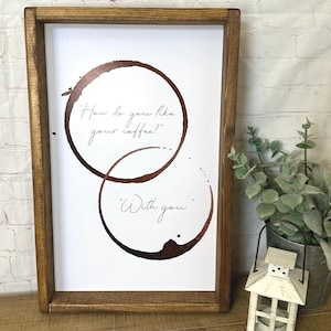 Puede incluir: Una impresión enmarcada con un diseño de mancha de café. La impresión dice "¿Cómo te gusta tu café?" y "Contigo."