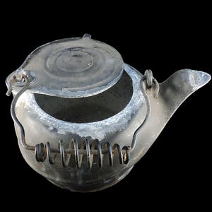 May include: A vintage metal teapot with a hinged lid and a curved spout. The handle has a spring coil for heat protection. The teapot is a dark gray color with white residue around the rim, suggesting age and use.