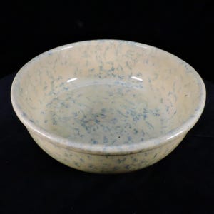 May include: A large, round, cream-colored ceramic bowl with a blue and white marbled glaze.