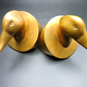 May include: A pair of gold-toned metal duck bookends. The ducks are facing opposite directions and have a simple, abstract design.