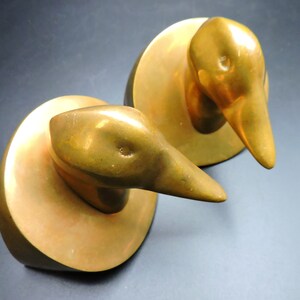May include: Two gold-colored metal duck bookends. Each duck is perched on a round base.
