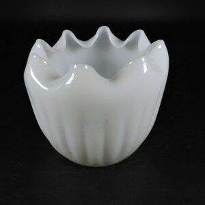 May include: A white, fluted, glass bowl with a scalloped rim. The bowl is made of opaque glass and has a smooth, glossy finish.