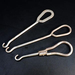 May include: A white ceramic mug with a black handle and the text "But First, Coffee" in a black, handwritten-style font. The mug is on a white surface.