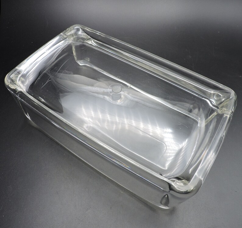 Op de afbeelding: Een rechthoekige bakvorm van helder glas met een deksel. De vorm is gemaakt van dik glas en heeft een glad, gepolijst oppervlak.