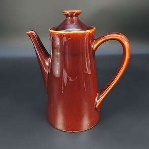 May include: A brown ceramic coffee pot with a lid and a handle. The pot has a glossy finish.