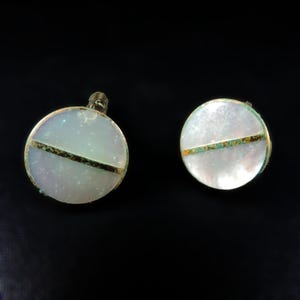 May include: A pair of round, white, mother-of-pearl earrings with a gold and green accent.