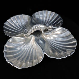 May include: Silver serving dish shaped like three scallop shells with a lobster in the centre.