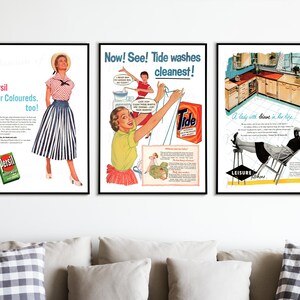 May include: Three framed vintage advertisements. The left ad features a woman in a striped skirt, the middle ad promotes Tide detergent, and the right ad shows a woman relaxing in a kitchen. The ads are displayed above a sofa with pillows.
