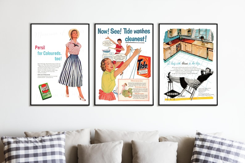 May include: Three framed vintage advertisements. The left ad features a woman in a striped skirt, the middle ad promotes Tide detergent, and the right ad shows a woman relaxing in a kitchen. The ads are displayed above a sofa with pillows.