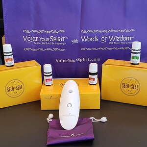 May include: A white diffuser with a purple pouch and three small bottles of essential oils. The bottles are labeled "Orange", "Grapefruit", and "Lime". The diffuser is labeled "Young Living". The boxes are labeled "Seed to Seal" and "Voice Your Spirit".