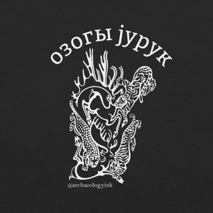 Könnte beinhalten: Ein schwarzes T-Shirt mit einem weißen Grafikdruck, der einen von zwei Tigern gejagten Hirsch zeigt. Über der Illustration steht der Text "озогы jурук" in Weiß, und am unteren Rand ist der Text "@archaeologyink" in kleinen weißen Buchstaben gedruckt.