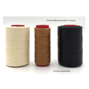 Puede incluir: Una taza de cerámica blanca con un asa negra y el texto "But First, Coffee" en un estilo manuscrito. La taza está sobre una superficie blanca. La taza mide aproximadamente 10 cm de alto.