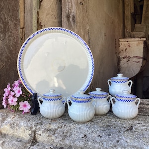 Könnte beinhalten: Ein Set aus sechs weißen Porzellan-Gewürzgläsern mit blauem und goldenem Besatz, angeordnet auf einem weißen Porzellan-Serviertablett mit blauem und goldenem Besatz. Die Gläser haben Deckel und sind alle gleich groß.