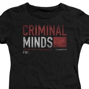 May include: Black t-shirt with a white graphic that says "Criminal Minds" with the words "Behavioral Analysis Unit" and "Quantico" underneath. The graphic is in a distressed style.