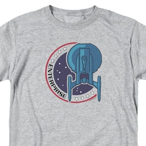 May include: A heather grey t-shirt with a blue and white graphic of a spaceship with the text "ENTERPRISE" in a circle.