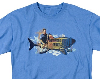May include: A light blue t-shirt with a graphic of a shark and a person riding on top of it. The text "Survivors ready... GO!" is printed on the shark.