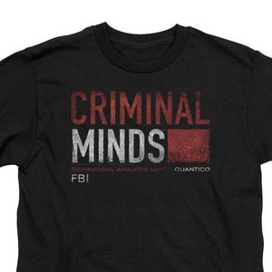 May include: Black t-shirt with a white and red graphic print that says "Criminal Minds" with the text "Behavioral Analysis Unit FBI Quantico" underneath.