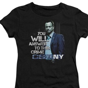 May include: Black t-shirt with a graphic of a man in a suit and the text "You Will Answer To This Crime CSINY".