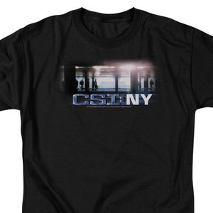 May include: Black t-shirt with a graphic of the show "CSI: NY" in white text. The graphic features a blurry image of a city street with people walking.