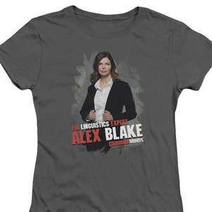 May include: A dark gray t-shirt with a graphic of a woman in a black suit and white shirt. The text "FBI Linguistics Expert Alex Blake Criminal Minds" is printed in red on the shirt.