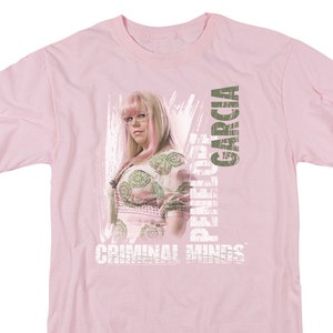 May include: Pink t-shirt with a graphic of Penelope Garcia from the TV show Criminal Minds. The graphic features a photo of Garcia with the text "Penelope Garcia" and "Criminal Minds" in a distressed font.