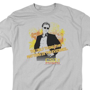 May include: A gray t-shirt with a graphic of a man in a suit and the text "The only thing that matters is the evidence. CSI: Miami"