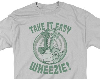 Puede incluir: Una camiseta gris claro con un gráfico verde de dos dragones con el texto "Take it easy Wheezie!"