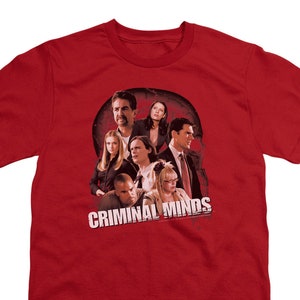 May include: Red t-shirt with a graphic of the cast of the TV show "Criminal Minds". The graphic features the main characters in a group shot, with the show's title in white letters.