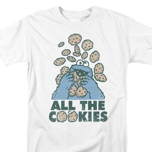 May include: White t-shirt with a blue Cookie Monster character eating cookies. The text "ALL THE COOKIES" is printed below the character.