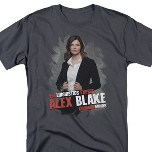 May include: A dark gray t-shirt with a graphic of a woman in a black blazer and white shirt. The text "FBI Linguistics Expert Alex Blake Criminal Minds" is printed in red on the shirt.